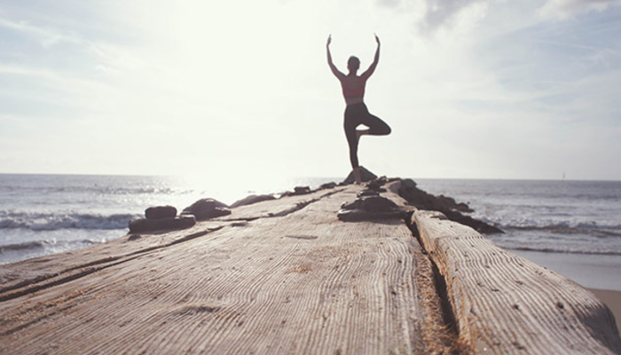 Man doing a yoga pose near water