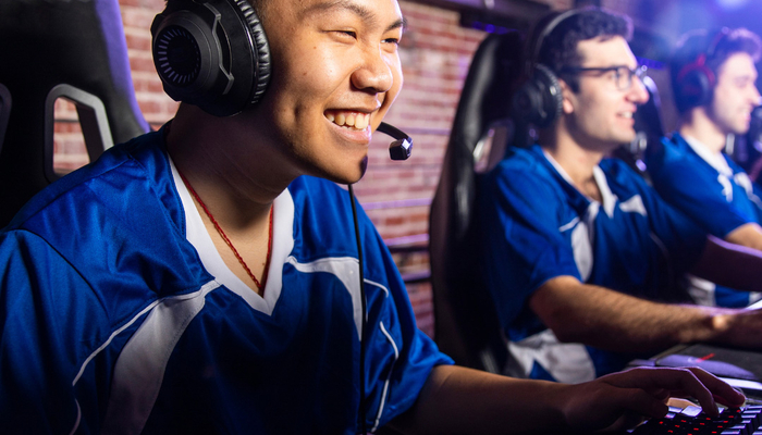 Students in gaming chairs smiling over their computers.