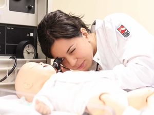 Nursing student examining SIM Baby