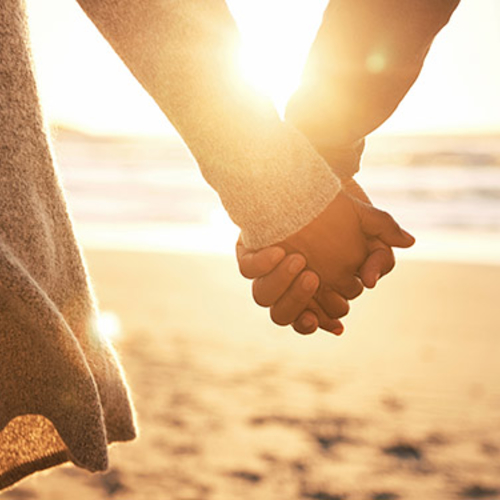 Couple holding hands at the beach at sunset