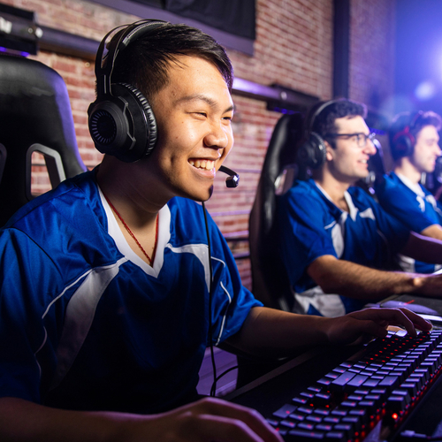 Students in gaming chairs smiling over their computers.